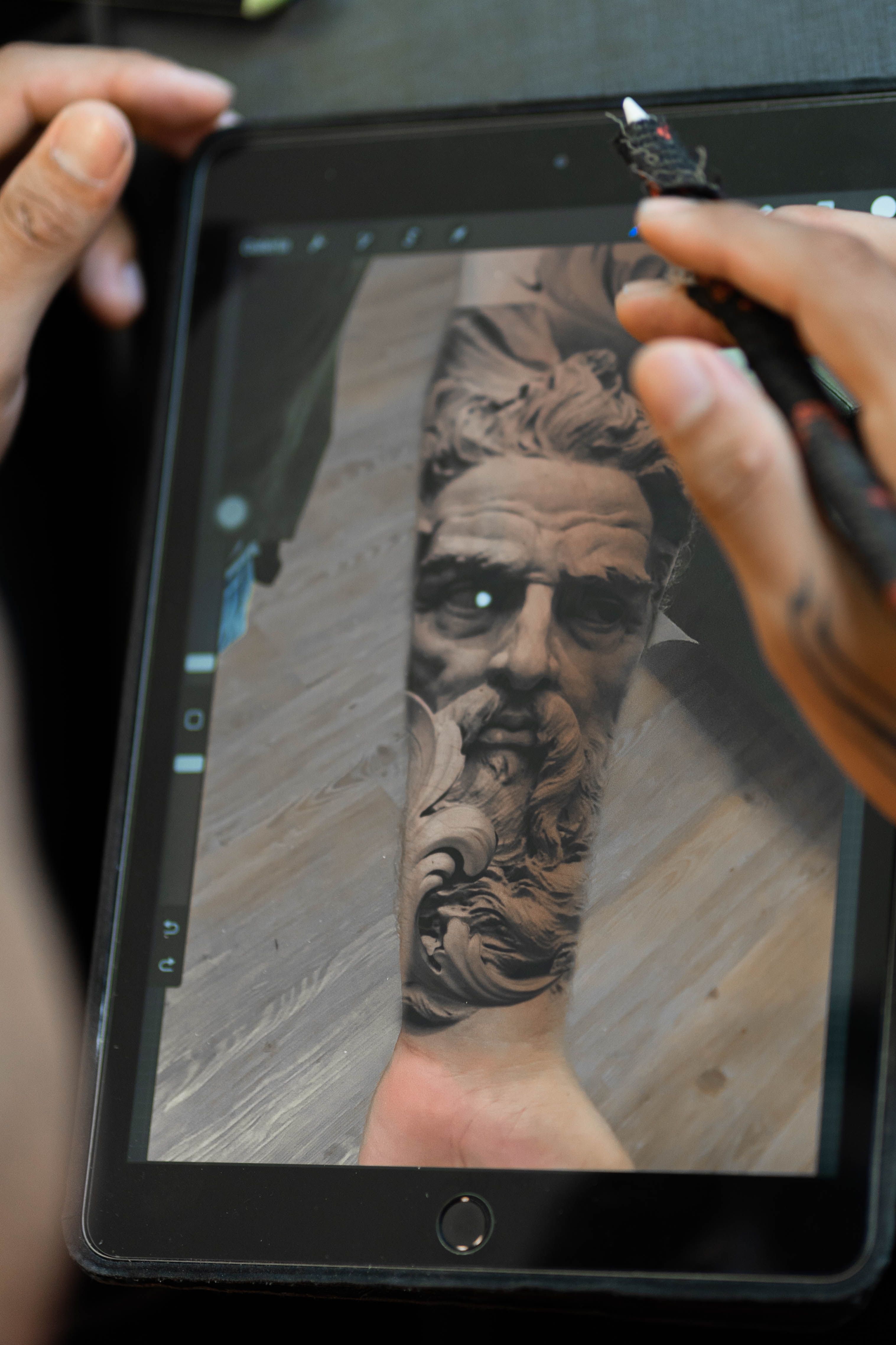 Tatuador desenvolvendo projeto de retrato realista em tablet com Procreate em estúdio